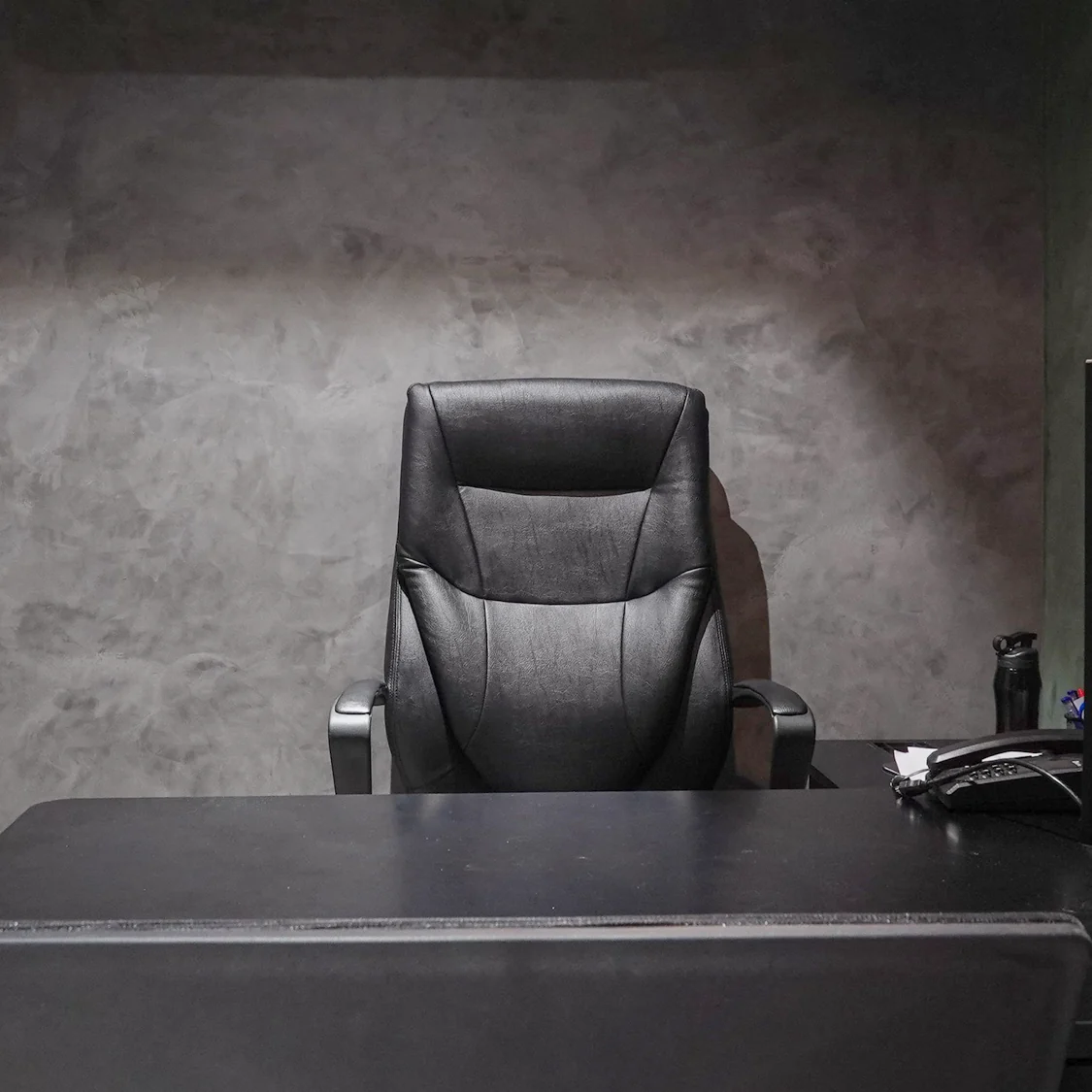 An unoccupied office, the desk chair empty and the monitor switched off